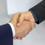 Outsourcing rekrutacji do agencji pracy – realne oszczędności czasu i pieniędzy Uścisk dłoni dwóch biznesmenów symbolizujący współpracę z agencją pracy