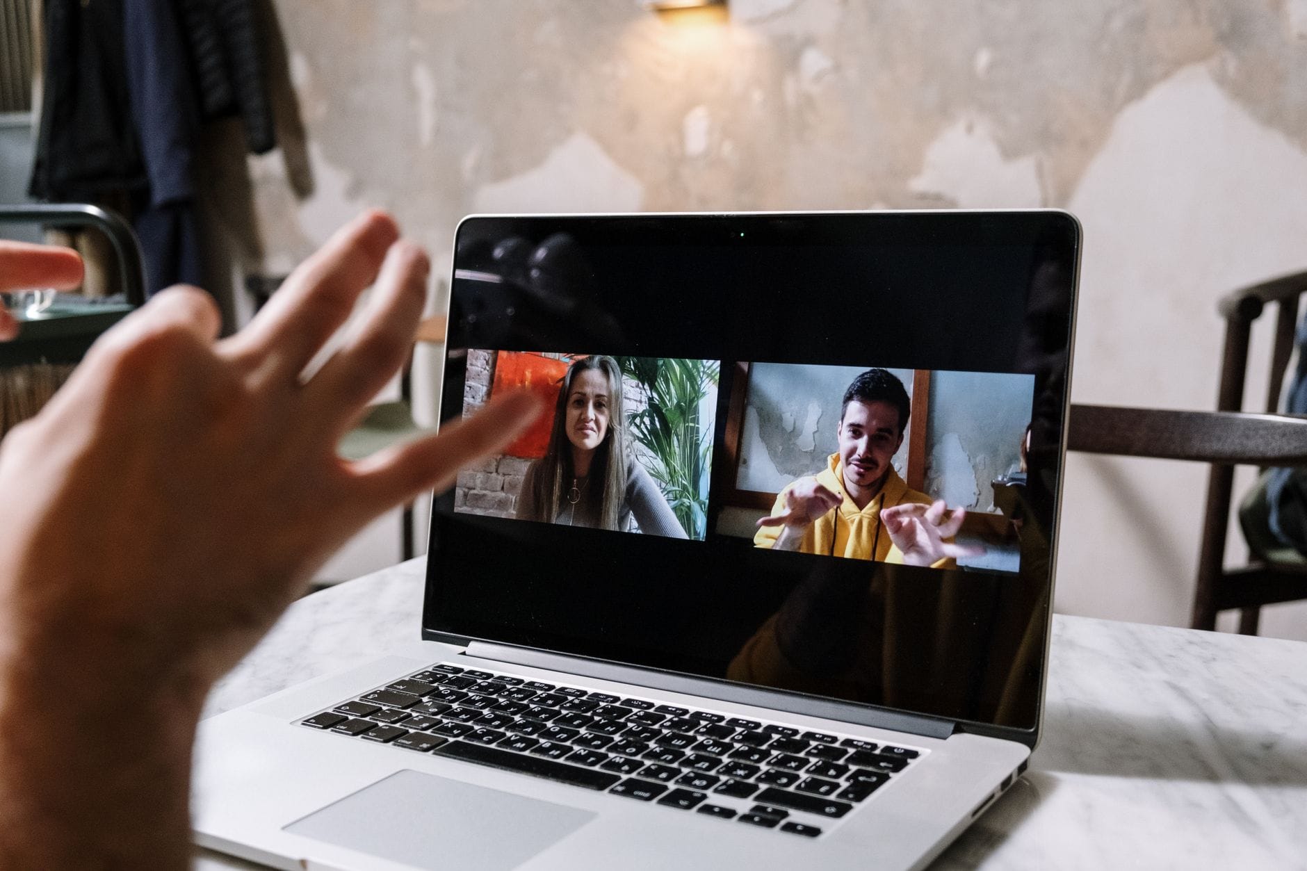 Gestykulujące dłonie podczas wideorozmowy na ekranie laptopa