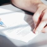 Jakich danych wymaga agencja pracy od pracodawcy i dlaczego to takie ważne Podpisywanie umowy długopisem na biurku z dokumentami